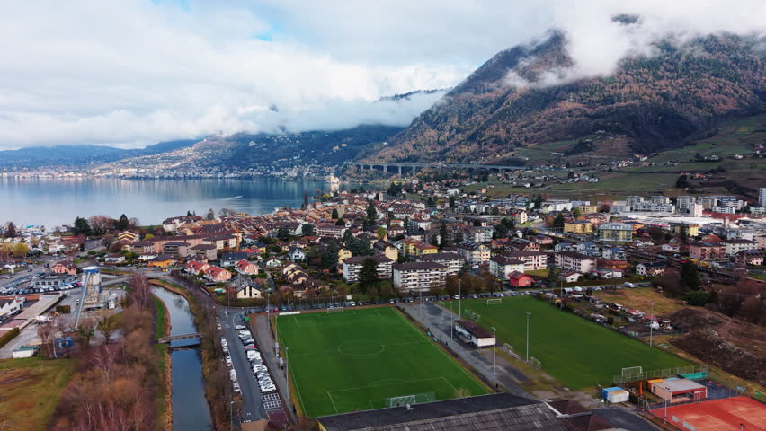 Aerial: Villeneuve cityscape and Lake Geneva during the day in Canton of Vaud, Switzerland, parallax drone shot