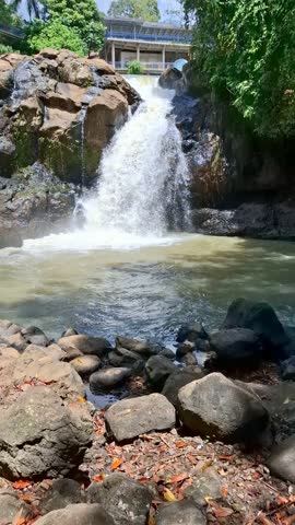 Waterfall cascades down rocky cliffs into a pool surrounded by lush greenery and trees creating a scenic and natural setting water flows providing an escape into nature