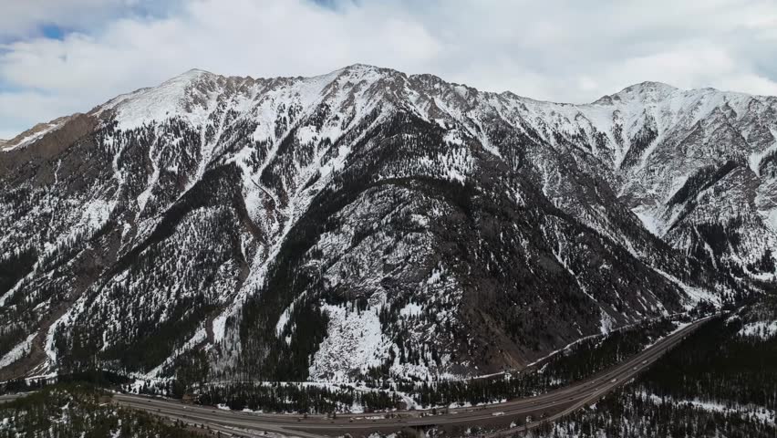 Snow covered alpine mountain slopes and forest valley at Officers Gulch near Frisco Colorado, panoramic pullback drone overview