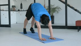 Determined sporty fit man performing pike push up exercise, strengthening shoulder muscles and improving core stability while working out in domestic room. - Powered by Shutterstock - Get 15% off with code: PIKWIZARD15