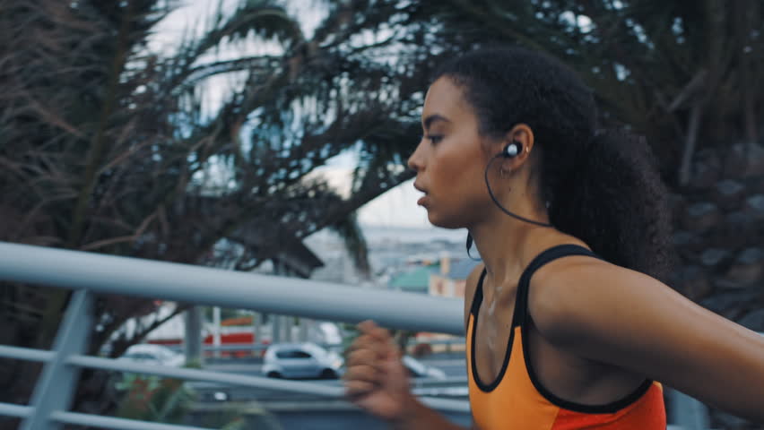 Fitness, running or woman on bridge with earphones, cardio playlist or stamina exercise in speed activity. Fast, streaming or athlete with intense sprint, sports podcast or endurance workout in city.