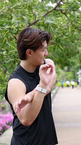 An athletic man performs arm stretches in a park walkway with soft natural daylight