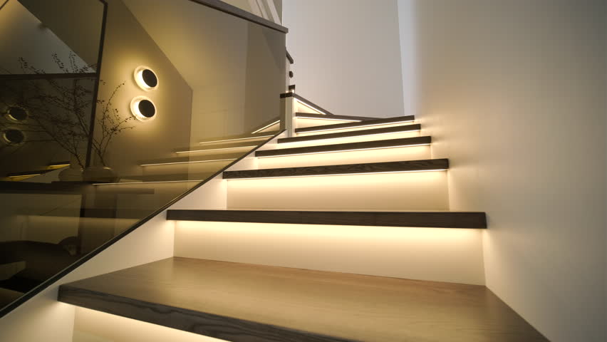 Modern interior design of a wooden staircase with integrated warm LED strip lighting, a glass balustrade, and a large mirror in a minimalist hallway.