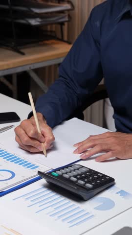 Professional accountant analyzing financial data, using a calculator and writing on a document