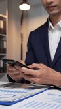 Close up of a businessman in a suit texting on a smartphone while analyzing financial charts - Powered by Shutterstock - Get 15% off with code: PIKWIZARD15