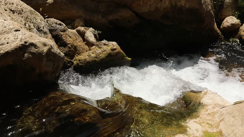 Close-up view of a small waterfall cascading over mossy rocks in a natural setting