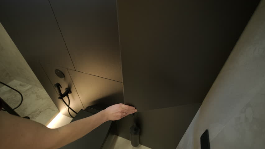 Luxury modern bathroom interior featuring a white freestanding bathtub and a unique stone vessel sink. The room is decorated with marble tiles, a large oval backlit mirror, and black matte fixtures in a minimalist contemporary style.