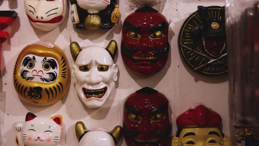 Traditional Japanese tourist souvenirs and gifts from Kyoto, Kansai, Japan, with daruma figures, kitsune fox, tengu mask, fridge magnets, toys figurines, key ring keychain, in a local vendor gift shop