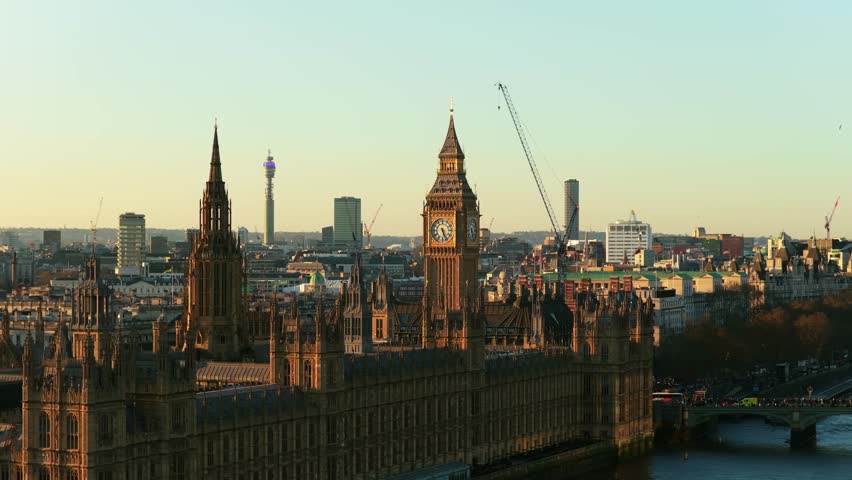 Golden hour illuminating Palace of Westminster and Elizabeth Tower, revealing London's historic architecture and River Thames flowing through the capital city