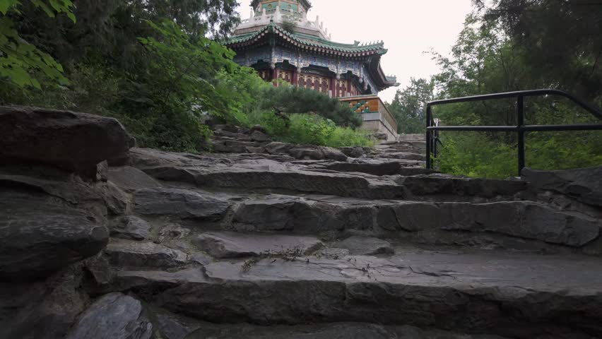 Stone stairway ascending through trees toward traditional pavilion in Fragrant Hills Park Beijing China