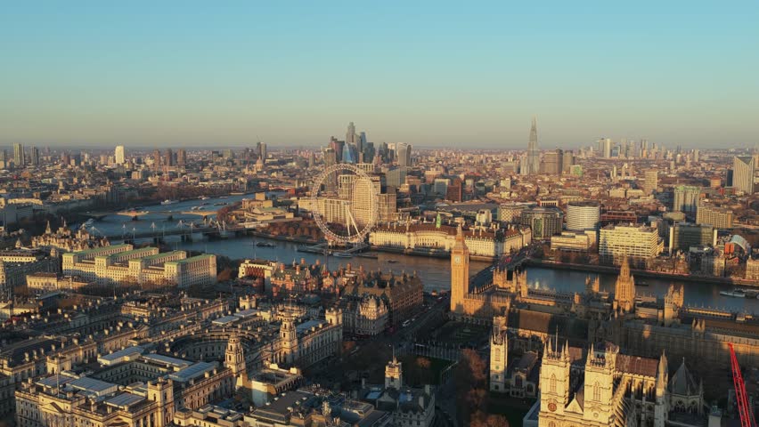 Golden hour light illuminating Central London landmarks including Westminster Abbey, River Thames, London Eye, Houses of Parliament, and City of London