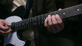 Close up guitarist hands playing chords and solo on fretboard of black and white electric guitar, with other hand strumming strings during musical performance. Musician playing an electric guitar solo - Powered by Shutterstock - Get 15% off with code: PIKWIZARD15