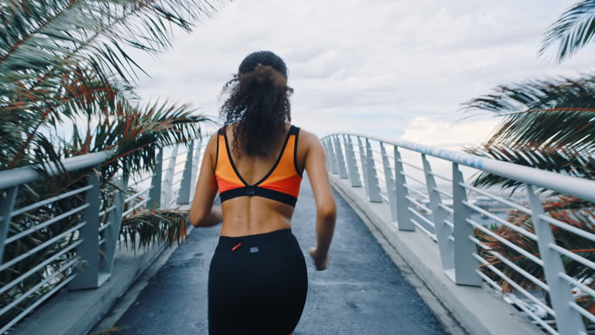 Fitness, back or runner on bridge with earphones, cardio playlist or stamina exercise in speed activity. Fast, intense sprint or woman with tech, sports podcast or endurance workout in city.