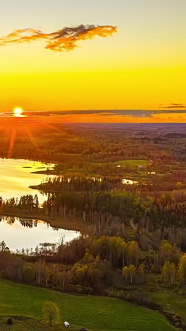 Sunrise over forest and winding river with golden light reflecting on water and landscape below