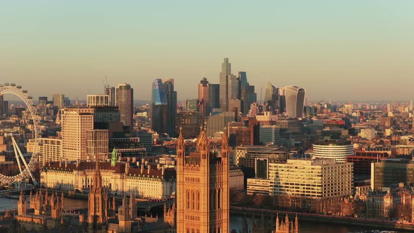 Golden hour illuminating central London cityscape, featuring the Houses of Parliament, Big Ben, Westminster Abbey, and City of London financial district skyline