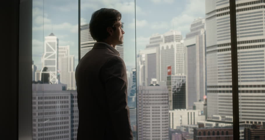 White Businessman in a Taupe Suit Stands by a Floor-to-ceiling Office Window, Thoughtfully Shaping Business Strategy and Startup Goals With Confidence, Ambition, Finance Insight and Success.