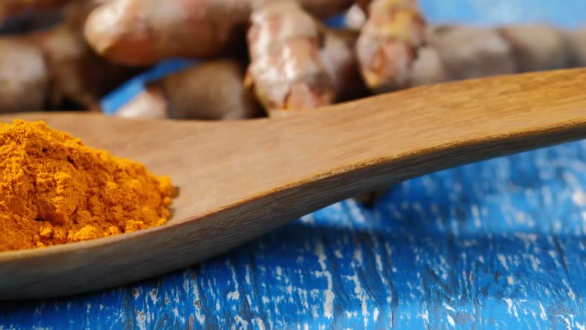 Turmeric powder in a wooden spoon