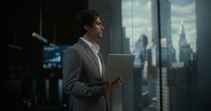 White Businessman in a Light Gray Suit Uses a Laptop in a High-rise Office, Focused on Startup Planning and Finance Strategy With a Subtle Smile, Expressing Ambition, Entrepreneurship and Success. - Powered by Shutterstock - Get 15% off with code: PIKWIZARD15
