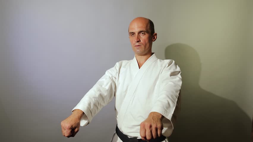 Against a light background, a young athlete in a standing position makes blocks and strikes in motion