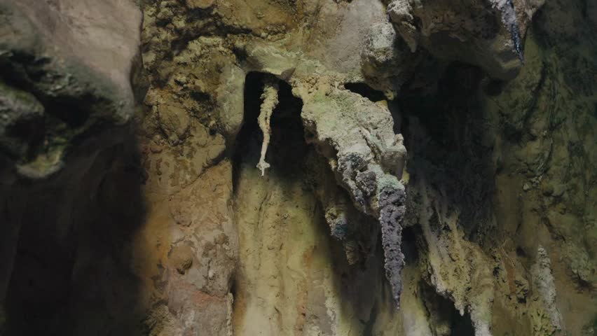 Close-up of stalactites hanging from a cave ceiling. Natural rock formations create a dramatic underground scene, showcasing geological beauty and textured stone surfaces