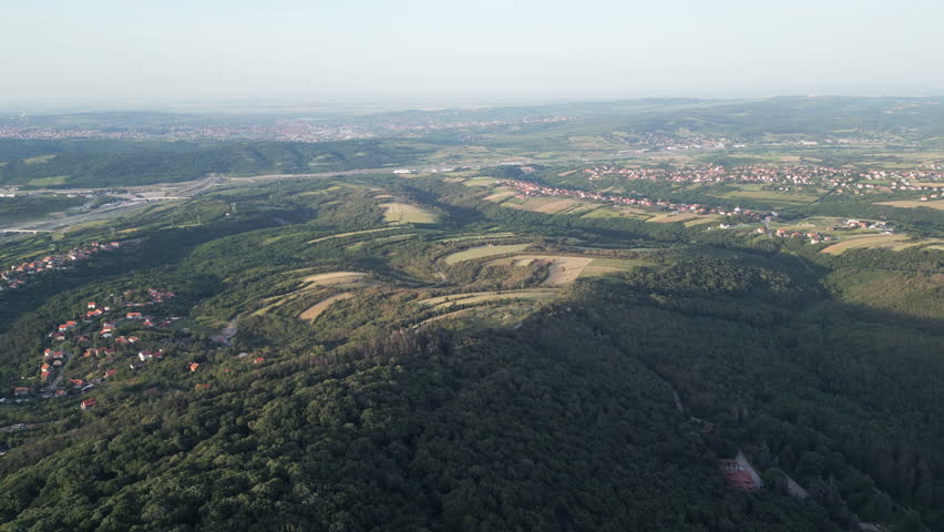 Scenic aerial view of the lush green Avala mountain slopes in Belgrade, Serbia, illuminated by warm late afternoon sunlight.