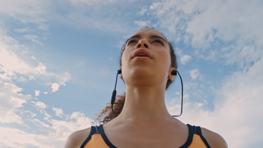 Woman, stretching and earphones outdoor with wellness, workout start or prepare for cardio training. Low angle, female person or runner warm up with fitness, audio tech or getting ready for exercise.