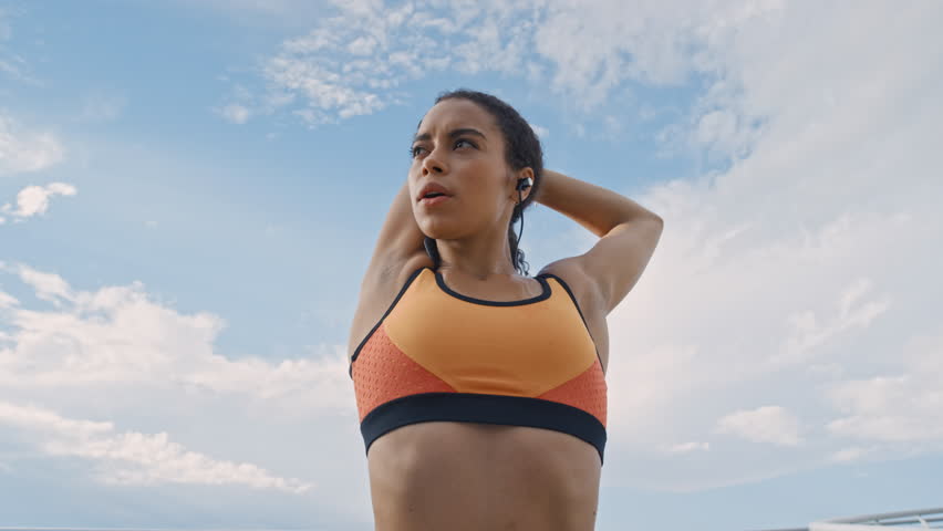 Woman, stretching and earphones in city with wellness, workout start or prepare for cardio training. Low angle, person or runner warm up outdoor with fitness, audio tech or getting ready for exercise
