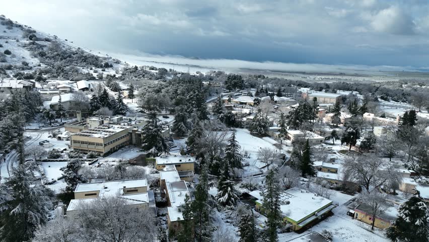 Aerial view of Merom Golan and Bental Reservoir covered in snow with wind turbines rising above the fog, Golan Heights, Israel