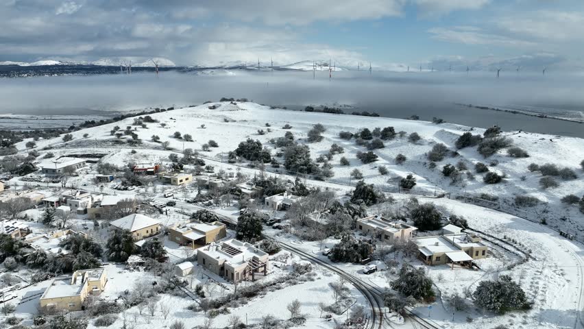 Aerial view of Merom Golan and Bental Reservoir covered in snow with wind turbines rising above the fog, Golan Heights, Israel