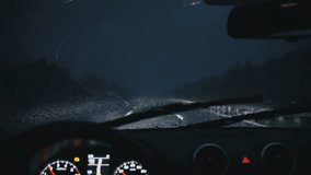 Point of view of a driver at night in heavy rain with windshield wipers clearing water on a dark highway, close interior dash and speedometer visible for automotive safety, transportation and weather - Powered by Shutterstock - Get 15% off with code: PIKWIZARD15