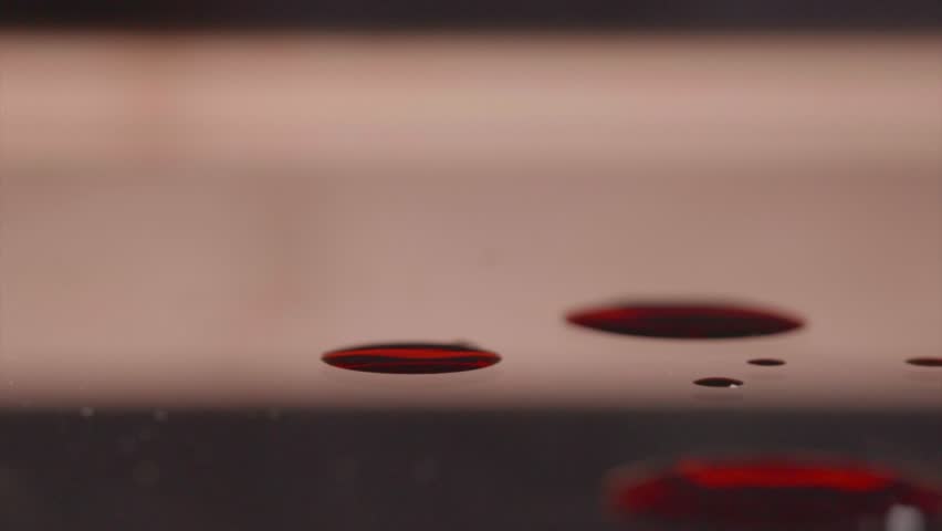 Blood drop spreading on a dark reflective surface showcasing its fluid dynamics and scientific properties Ideal for medical research and forensic concepts