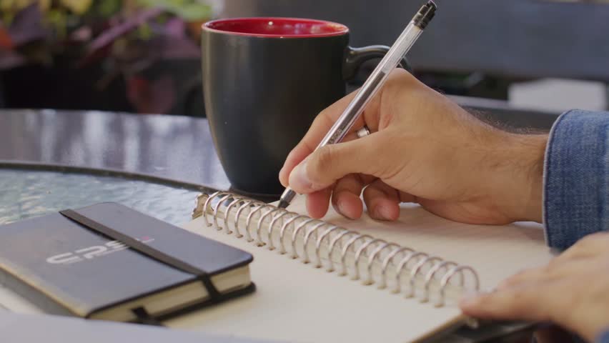 close up hands writing on note by pen