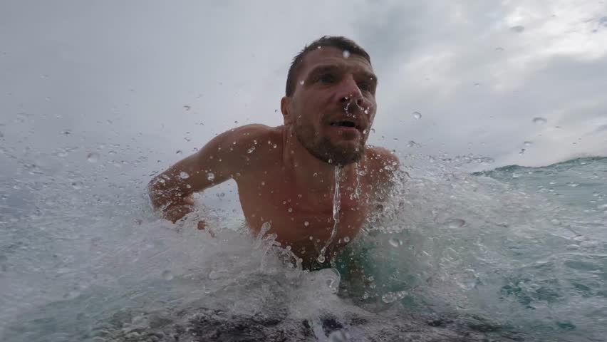 Man surfer on black surfboard rides a wave in ocean.