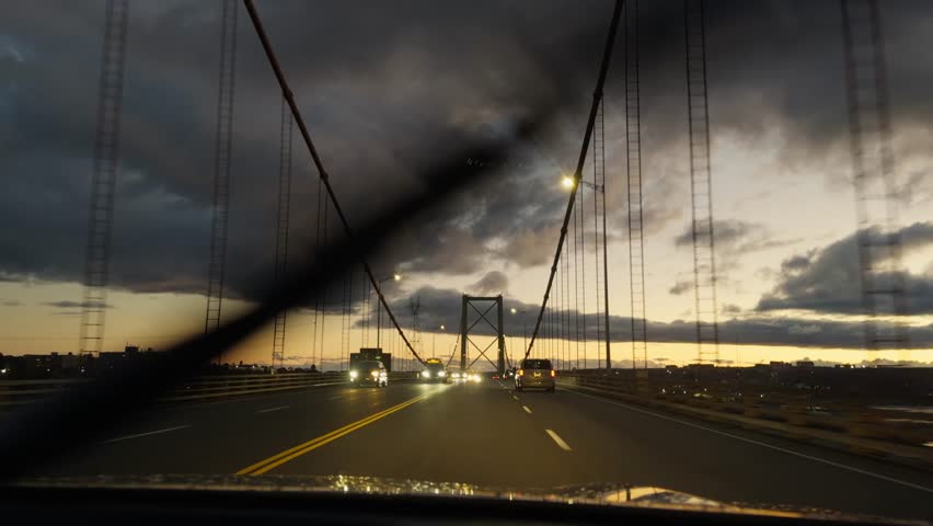 POV night drive through rainy Halifax streets and bridges. Raindrops continuously run down the windshield, colorful city lights reflect on wet glass, immersive rainy night in Nova Scotia, Canada 4K.