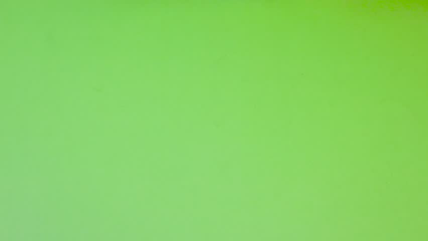 A detailed top-down view features a pair of hands presenting Ghanaian currency against a vibrant green backdrop. One hand holds a crisp, pink One Cedi banknote prominently displaying the "Big Six" historical figures, while the other hand holds a circular, two-toned Cedi coin. The composition is steady and brightly lit, making it ideal for financial or cultural content. The contrast between the pink paper, the metallic coin, and the lime-green surface creates a sharp, professional look.