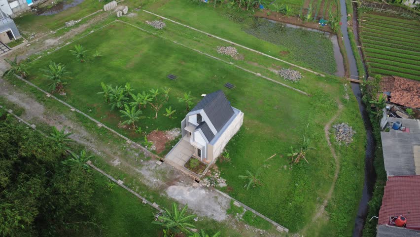 Jakarta, Indonesia - April 09, 2026: Wide aerial drone shot orbiting a modern minimalist house from a distance, showcasing the property