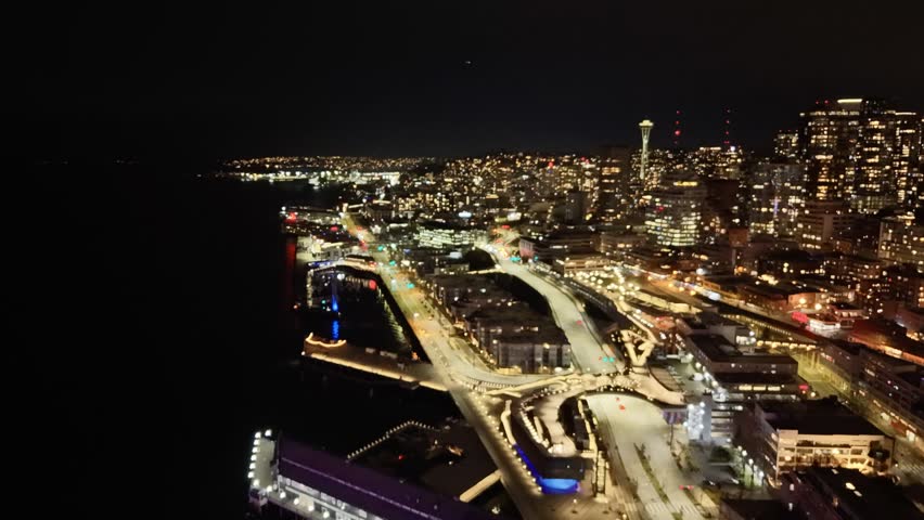 Seattle downtown skyline and waterfront with illuminated ferris wheel reflecting on Elliott Bay at night aerial view. g.
