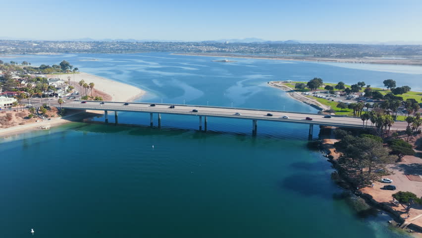 Coastal bridge over Mission Bay in San Diego captured in morning aerial view with calm water surrounding land and soft sunlight highlighting urban waterfront landscape.