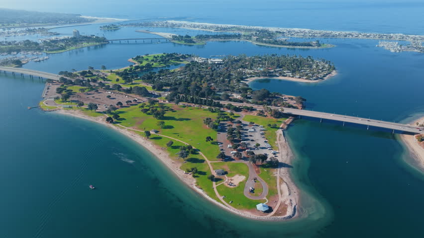 Mission Bay island with bridge connection in San Diego captured from aerial view during morning with calm water and green park areas forming scenic coastal landscape.