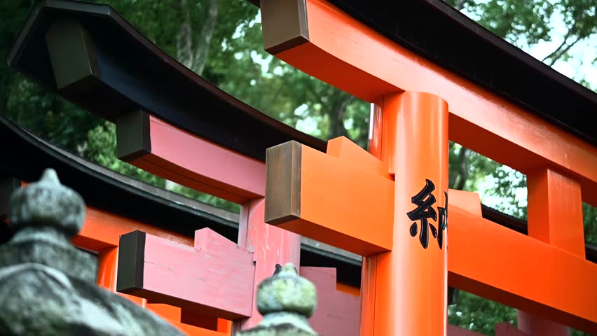 This is a detailed view of Fushimi Inari Taisha in Kyoto, Japan, which is famous for its thousands of red Torii doors across forested mountains. This video shows the iconic trails, traditional shrine structures, images of Inari
