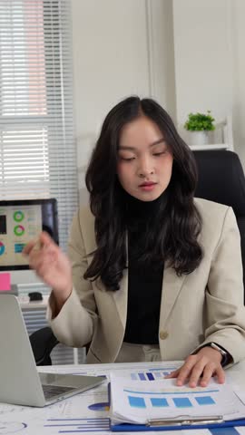 Young female accountant working with charts and graphs, checking financial reports on her laptop
