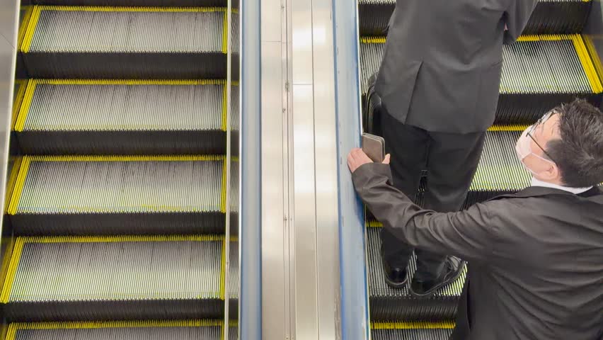 High angle shot of people in winter coats riding an escalator in a Japanese station
