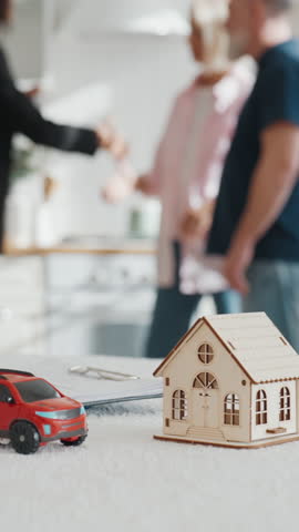 Happy people rejoicing by purchase or living house and car, hand over keys. Meeting of real estate agent and new homeowners, successful deal of sale and buy property, sign agreements on table
