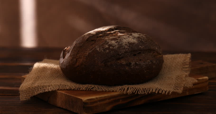 Loaf of fresh rye bread on wooden table, closeup