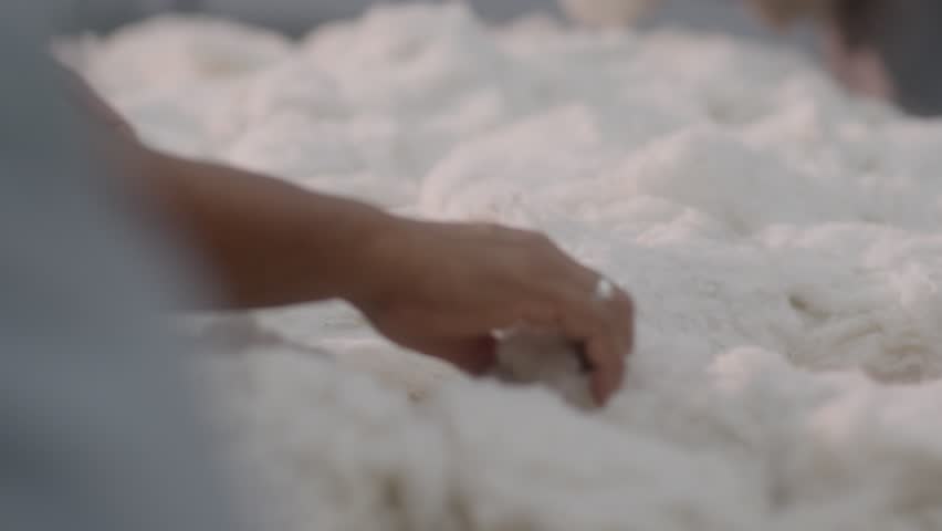Close-up view of a worker inspecting raw cotton material in a textile factory