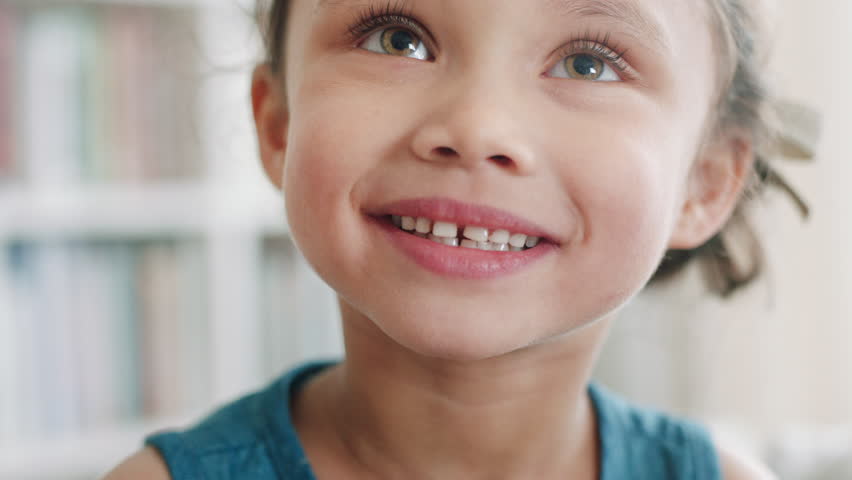 Laughing, face and child on break in home, adorable and growth of girl and happiness in living room. Portrait, smile and kid on peaceful weekend in lounge, development and comfortable in Canada
