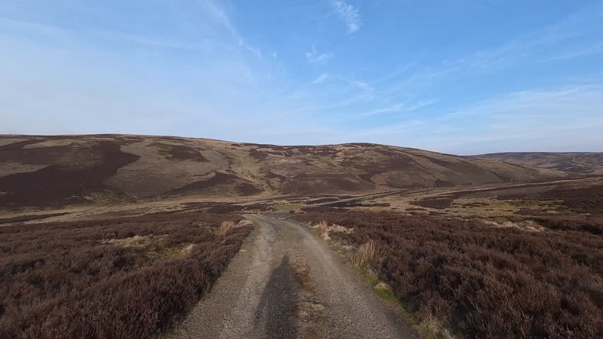 Scenic Pathway through Rolling Hills, Wide aerial view of a narrow dirt path winding through green rolling hills.