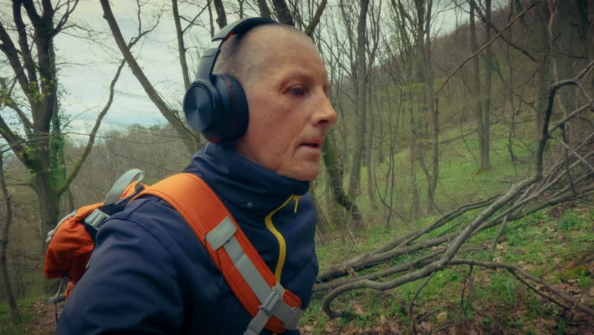 Solo traveler with a backpack and headphones exploring scenic hiking trails in a blooming spring woodland. Highlighting local tourism, weekend getaways, and outdoor exploration.