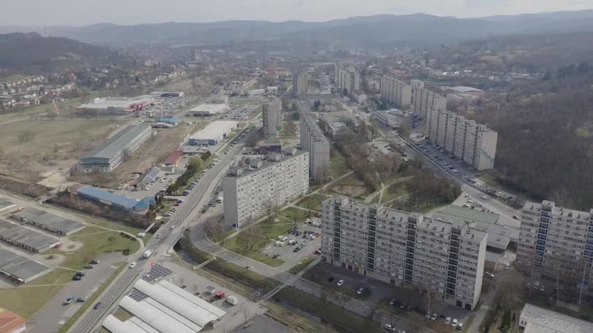 Aerial View of Urban Landscape and Mountain Range, Wide aerial panorama of a rugged mountain range under a clear blue sky.