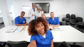 Cheerful group of diverse doctors and nurses taking a funny selfie with a smartphone, smiling and posing together during a break in a modern hospital meeting room after a medical congress - Powered by Shutterstock - Get 15% off with code: PIKWIZARD15